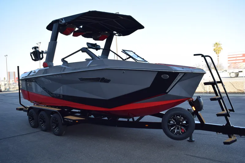 Slide: The Image of 2025 Nautique Super Air Nautique G23 boat on trailer, sleek design, gray and red color scheme. - 2