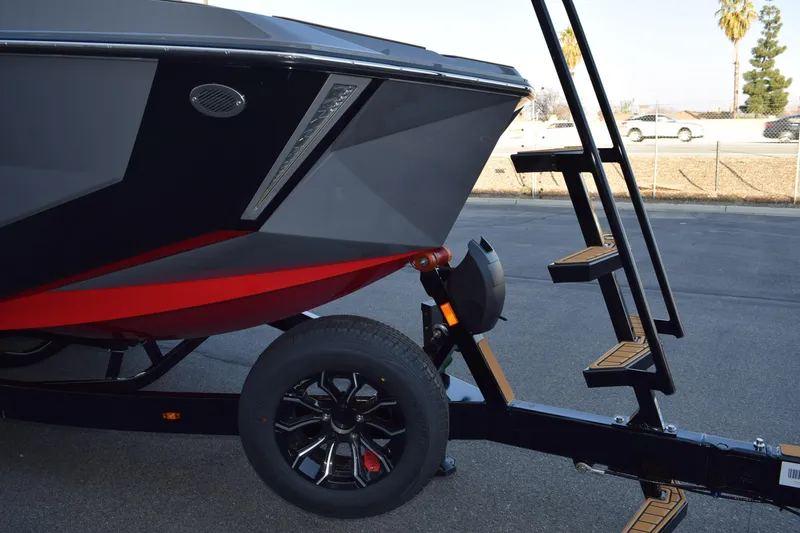 Slide: The Image of 2025 Nautique Super Air Nautique G23 boat on trailer with ladder, black and red design. - 3