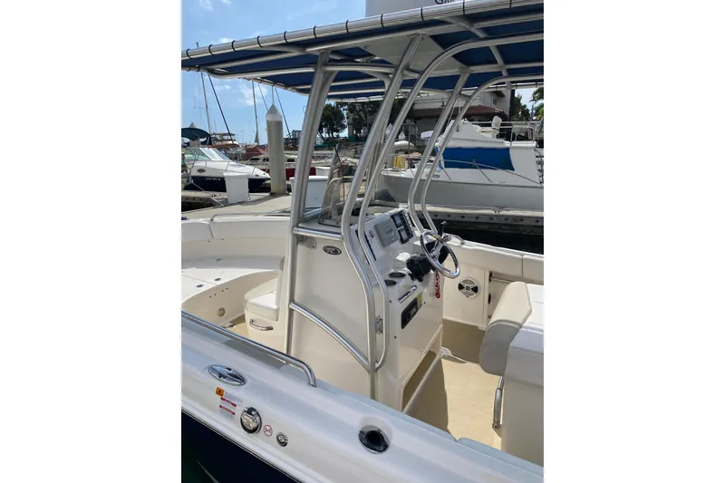 Slide: The Image of 2014 Robalo R222 Center Console boat docked, featuring steering console and seating area. - 12