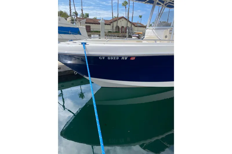 Slide: The Image of 2014 Robalo R222 Center Console boat docked with blue hull and registration number. - 3