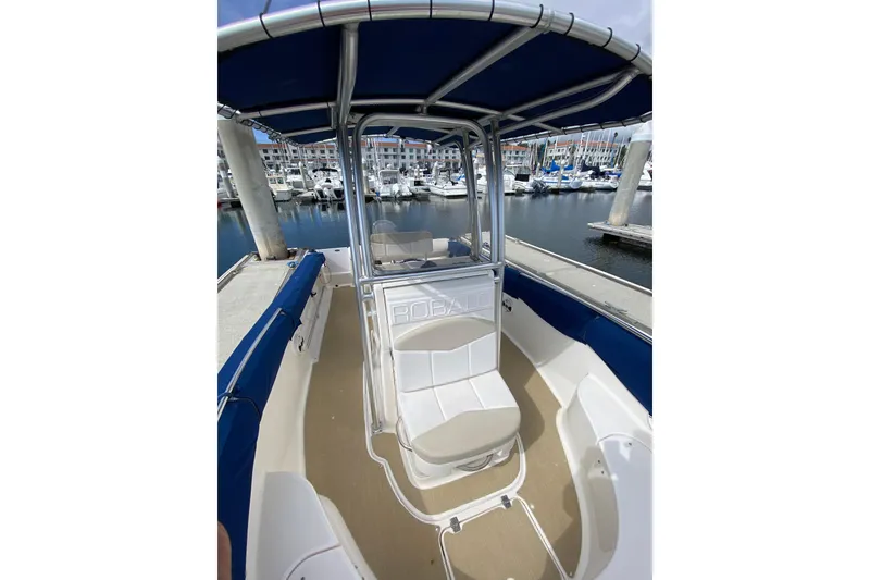 Slide: The Image of 2014 Robalo R222 Center Console boat docked at marina, featuring blue canopy. - 5