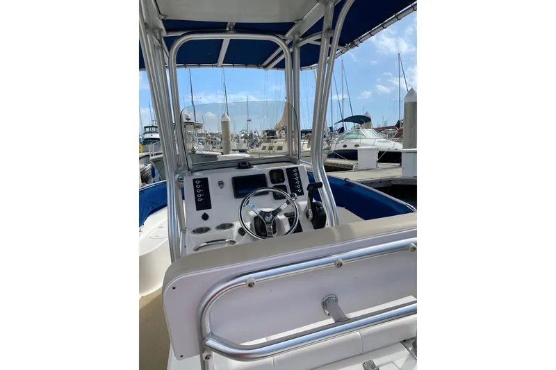 Slide: The Image of 2014 Robalo R222 Center Console boat interior at marina, featuring steering wheel and controls. - 9