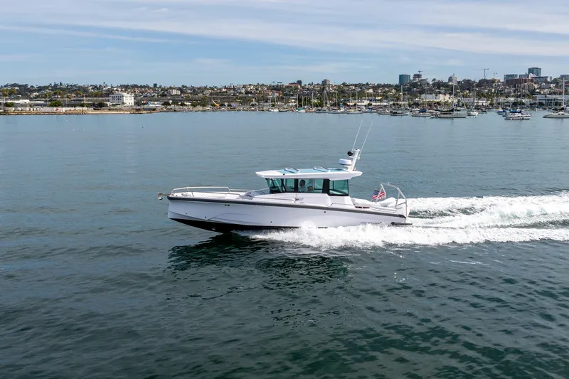 Slide: The Image of 2026 Axopar 29 XC Cross Cabin cruising on a calm coastal waterway. - 5