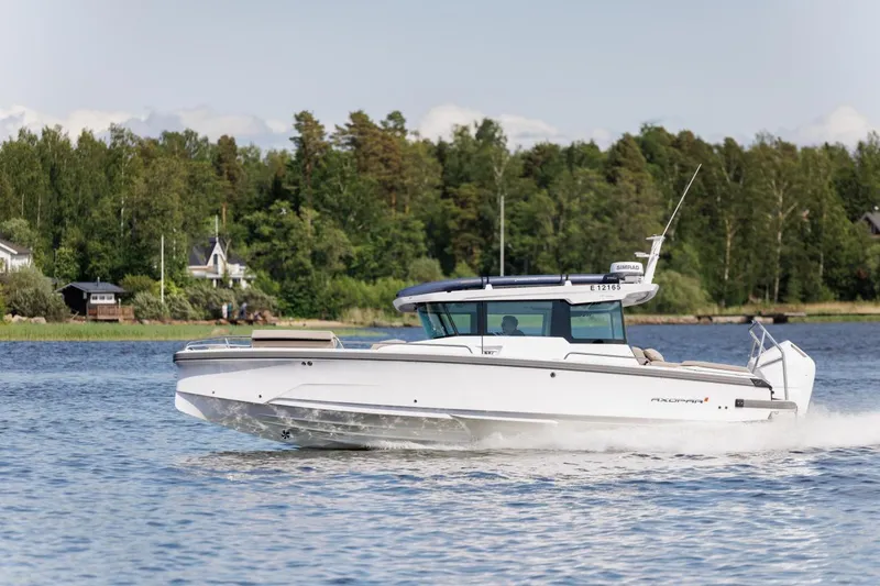 Slide: The Image of 2026 Axopar 29 XC Cross Cabin cruising on a serene lake with lush greenery. - 4
