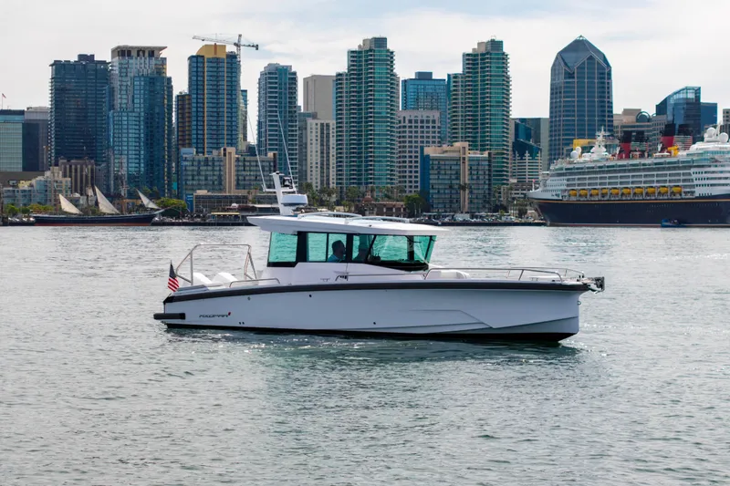 Slide: The Image of 2026 Axopar 29 XC Cross Cabin boat cruising near city skyline and large cruise ship. - 1