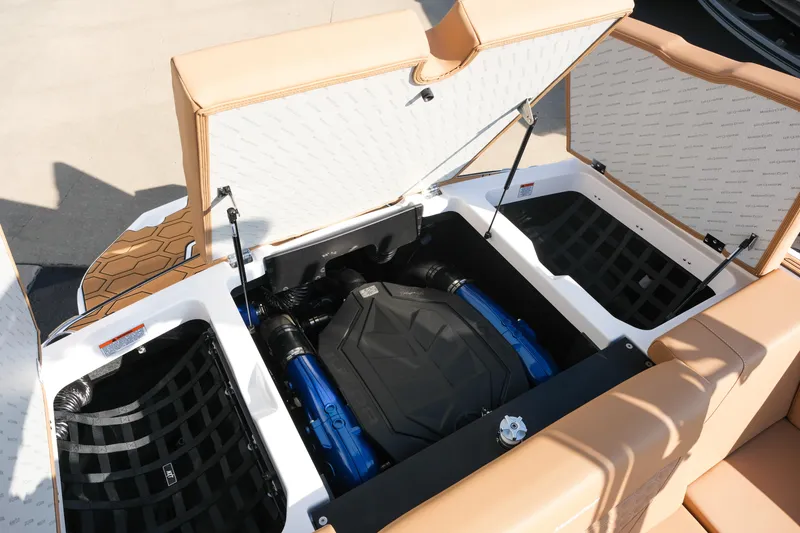 Slide: The Image of 2026 MasterCraft NXT23 boat engine compartment with tan seating and storage areas. - 14