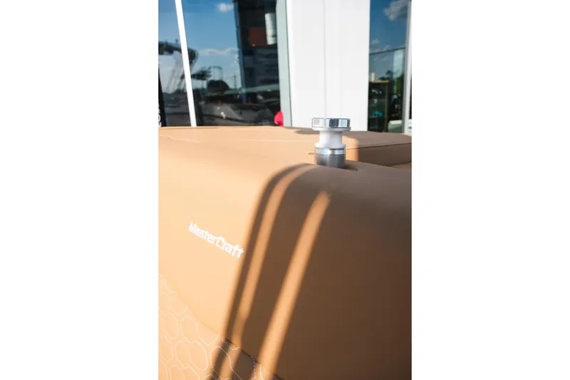 Slide: The Image of 2026 MasterCraft NXT23 boat detail with tan upholstery and chrome hardware. - 17