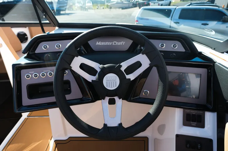 Slide: The Image of Steering wheel and dashboard of 2026 MasterCraft NXT23 boat, featuring modern controls and displays. - 24