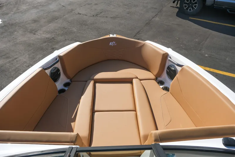 Slide: The Image of 2026 MasterCraft NXT23 boat interior with tan seating and cup holders. - 30