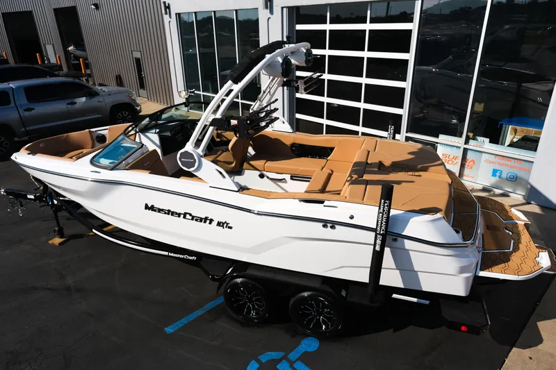 Slide: The Image of 2026 MasterCraft NXT23 boat with tan interior, parked outside a showroom. - 4