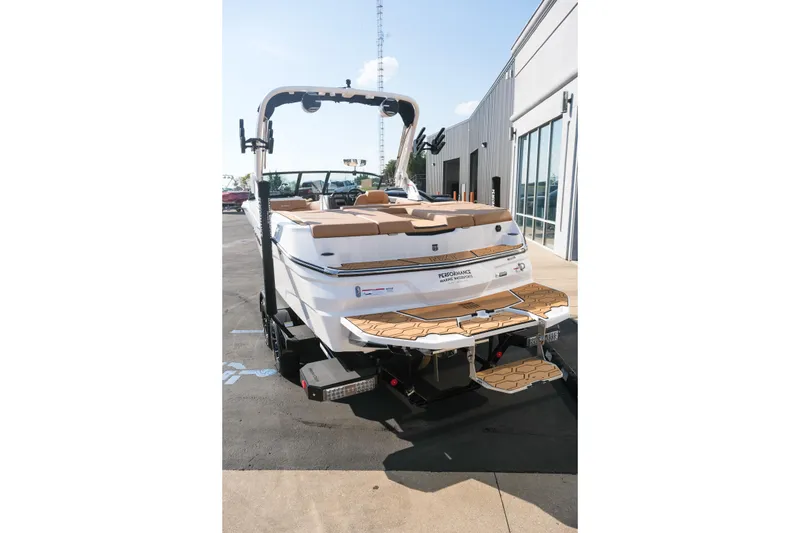 Slide: The Image of 2026 MasterCraft NXT23 boat, rear view, parked outdoors near a building. - 6