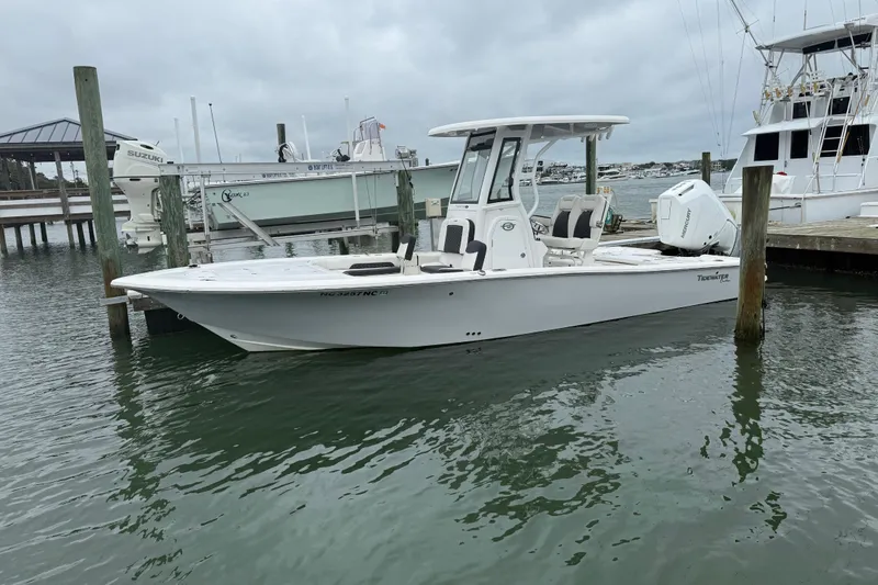 Slide: The Image of 2024 Tidewater 2500 Carolina Bay boat on calm water, featuring a sleek design and Mercury engine. - 5