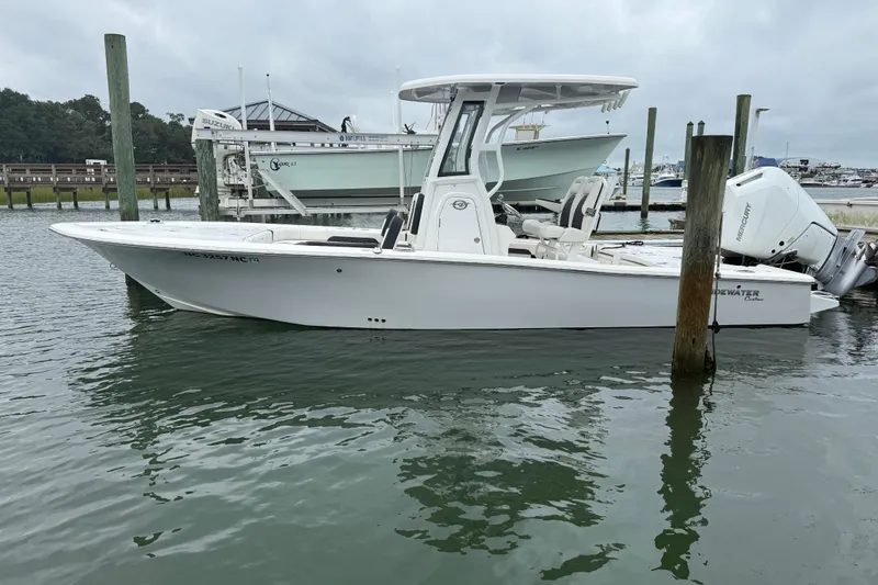 Slide: The Image of 2024 Tidewater 2500 Carolina Bay boat on calm water, featuring a powerful outboard motor. - 7