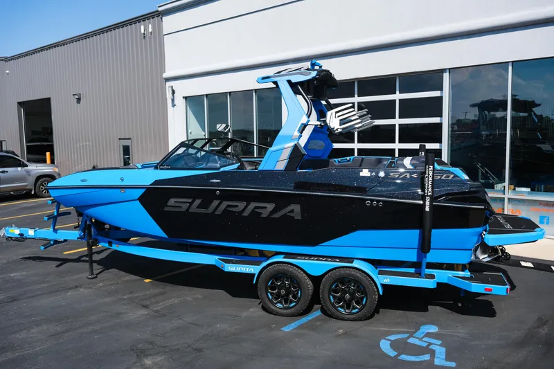 Slide: The Image of 2026 Supra SA450 boat in blue and black on a trailer outside a building. - 3