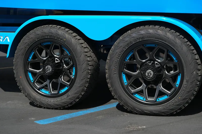 Slide: The Image of 2026 Supra SA450 wheels with black and blue rims, parked on asphalt. - 48