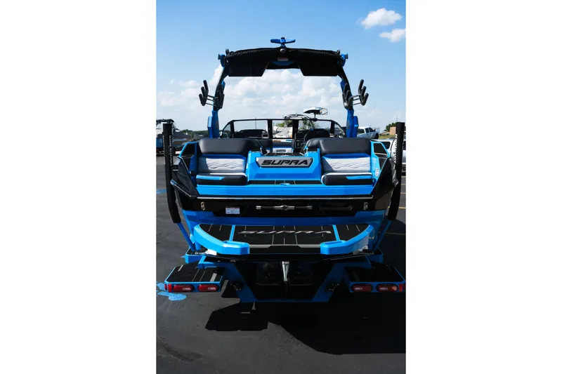 Slide: The Image of 2026 Supra SA450 boat, rear view, blue and black design, parked outdoors. - 5