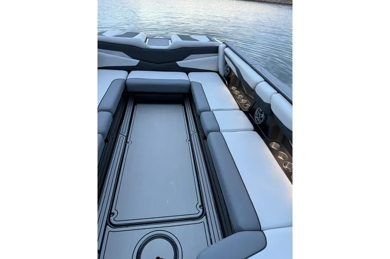 Slide: The Image of 2022 Axis T250 boat interior with cushioned seating and cup holders on a calm lake. - 2