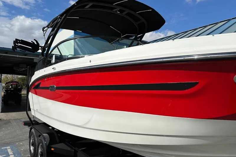 Slide: The Image of 2026 Sea Ray SDX 230 Surf boat with red and white exterior, parked on a trailer. - 7