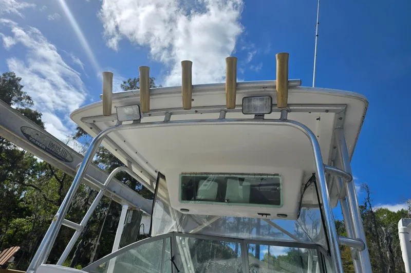 Slide: The Image of 1993 Robalo 2440 boat with rod holders and canopy under a clear blue sky. - 10