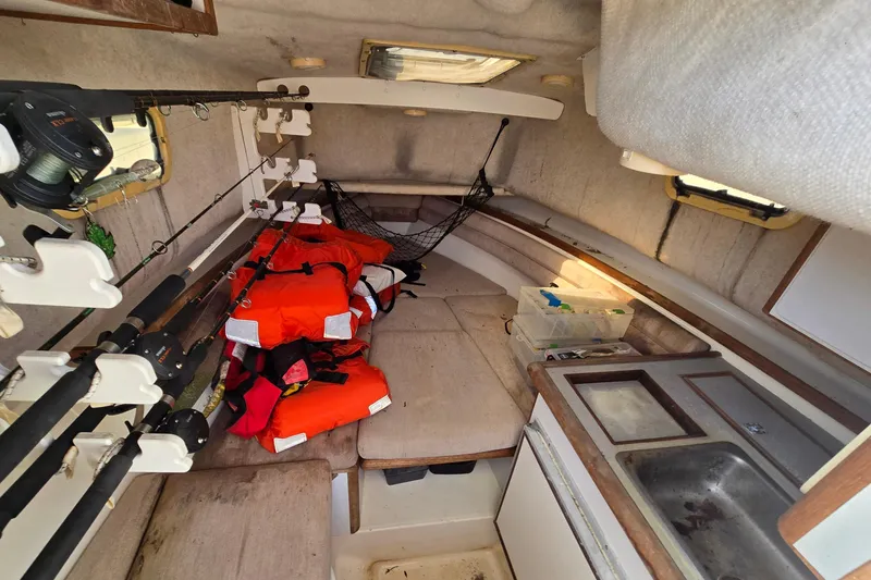 Slide: The Image of Interior of 1993 Robalo 2440 boat with fishing rods, life jackets, and kitchenette. - 22