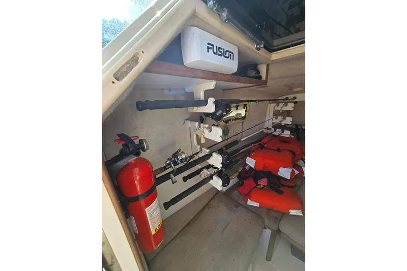 Slide: The Image of Interior of 1993 Robalo 2440 boat with fishing rods, life jackets, and fire extinguisher. - 24