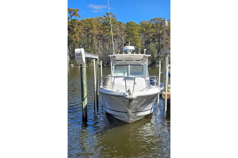 Slide: The Image of 1993 Robalo 2440 boat docked on calm water with trees in the background. - 25