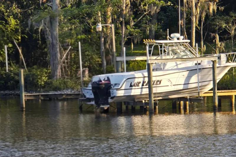 Slide: The Image of 1993 Robalo 2440 boat docked by a scenic, wooded shoreline. - 27