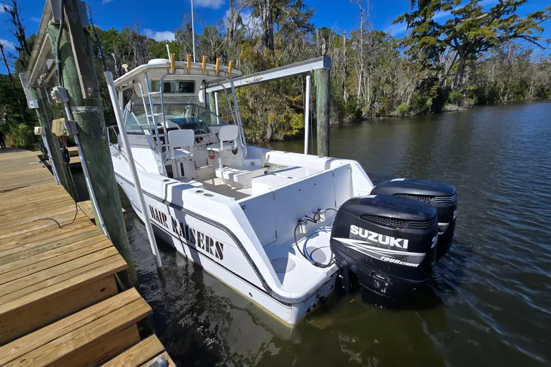 Slide: The Image of 1993 Robalo 2440 boat with twin Suzuki engines docked on a calm river. - 3