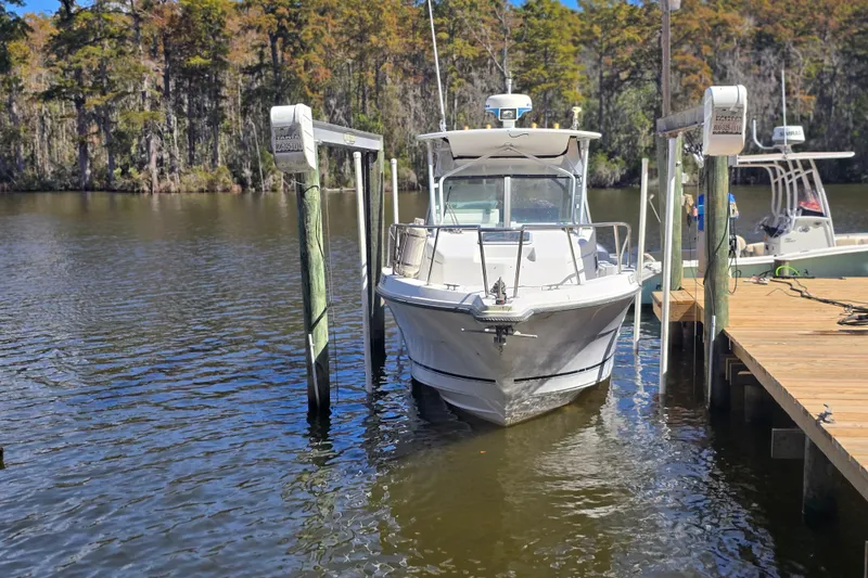 Slide: The Image of 1993 Robalo 2440 boat docked on a serene lake with lush forest backdrop. - 4