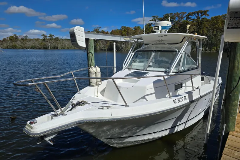 Slide: The Image of 1993 Robalo 2440 boat docked on a calm lake under a blue sky. - 6