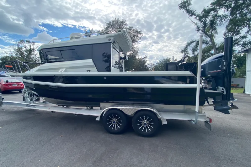 Slide: The Image of 2024 Sea King 260 boat on trailer, parked outdoors under cloudy sky. - 11