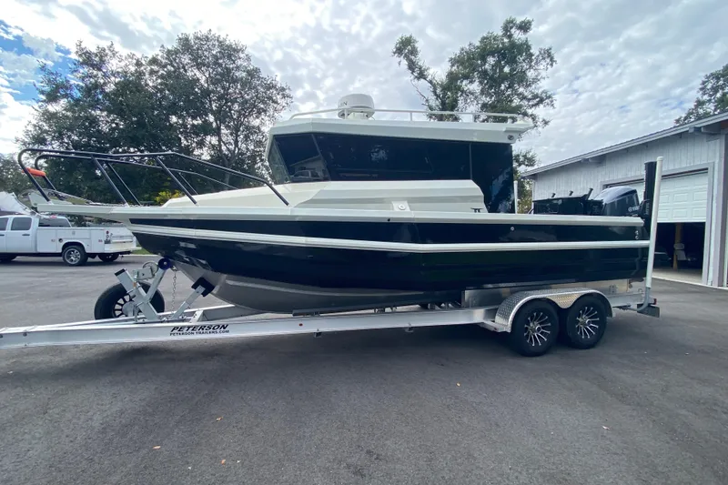 Slide: The Image of 2024 Sea King 260 boat on trailer, parked outdoors near trees and a garage. - 13