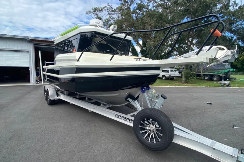 Slide: The Image of 2024 Sea King 260 boat on trailer, parked outdoors near a garage. - 14