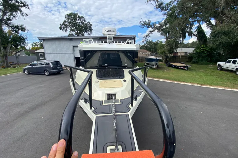 Slide: The Image of 2024 Sea King 260 boat on trailer, parked outdoors with trees and vehicles nearby. - 17