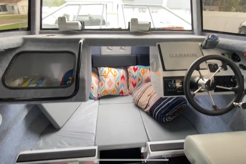 Slide: The Image of 2024 Sea King 260 boat interior with Garmin navigation, cozy seating, and colorful cushions. - 24