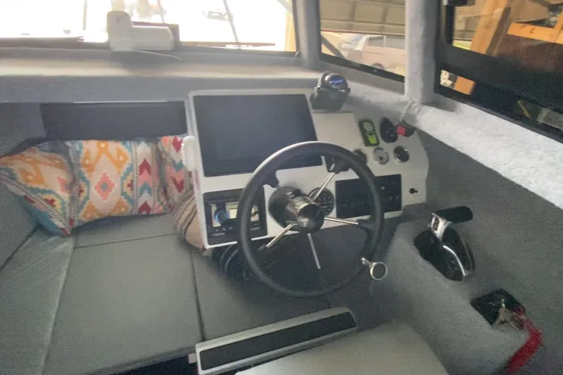 Slide: The Image of 2024 Sea King 260 boat interior with steering wheel, control panel, and colorful cushions. - 25