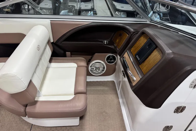 Slide: The Image of 2011 Cobalt 296 boat interior with brown and white seating, wood accents, and speaker. - 11