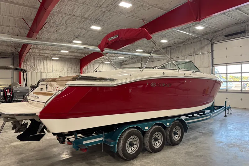 Slide: The Image of 2011 Cobalt 296 boat with red hull on trailer in indoor storage. - 3