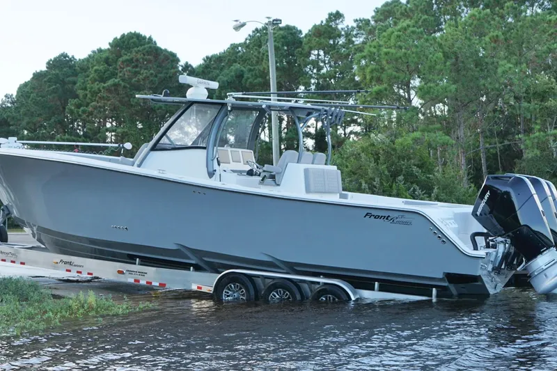 Slide: The Image of 2024 Front Runner 39 Center Console boat on trailer near water and trees. - 10