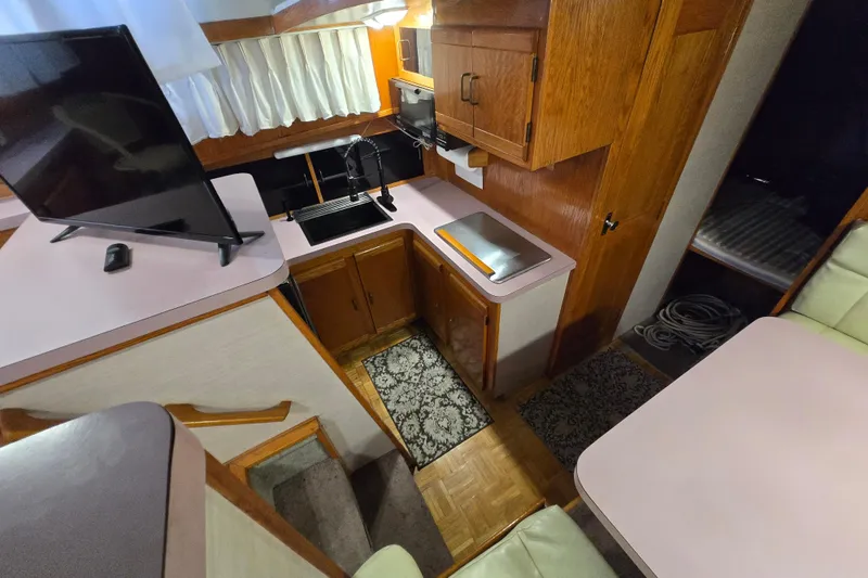 Slide: The Image of 1988 Mainship 36 Double Cabin interior with kitchen, TV, and wood cabinetry. - 11
