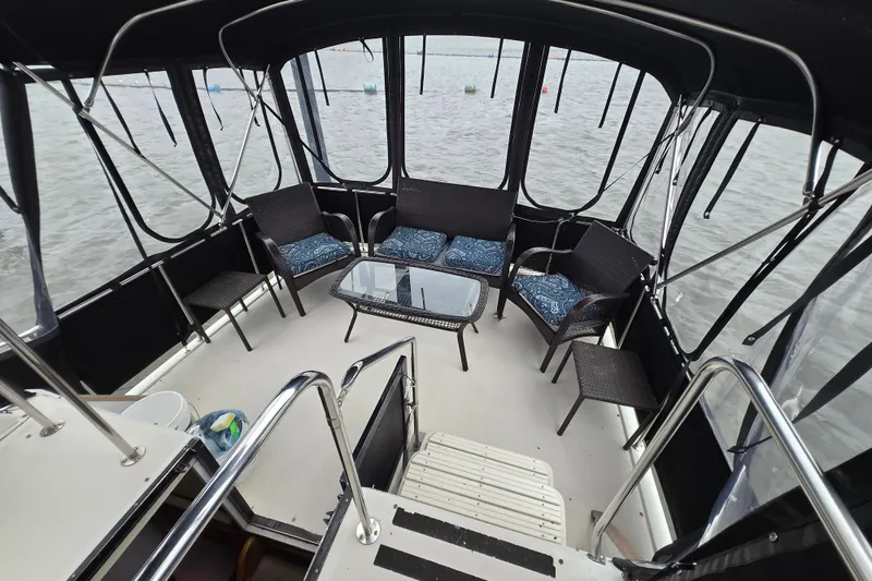 Slide: The Image of 1988 Mainship 36 Double Cabin boat interior with seating and glass table, overlooking water. - 13