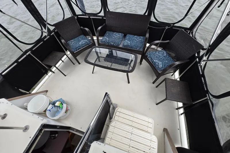 Slide: The Image of 1988 Mainship 36 Double Cabin deck with wicker seating and glass table, overlooking water. - 14