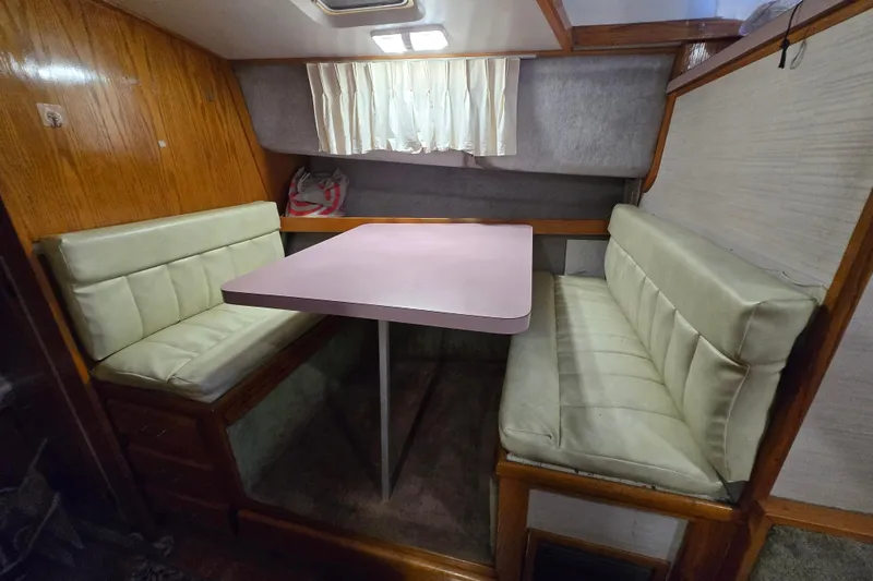 Slide: The Image of 1988 Mainship 36 Double Cabin interior with dining area, featuring cushioned seating and wooden accents. - 20