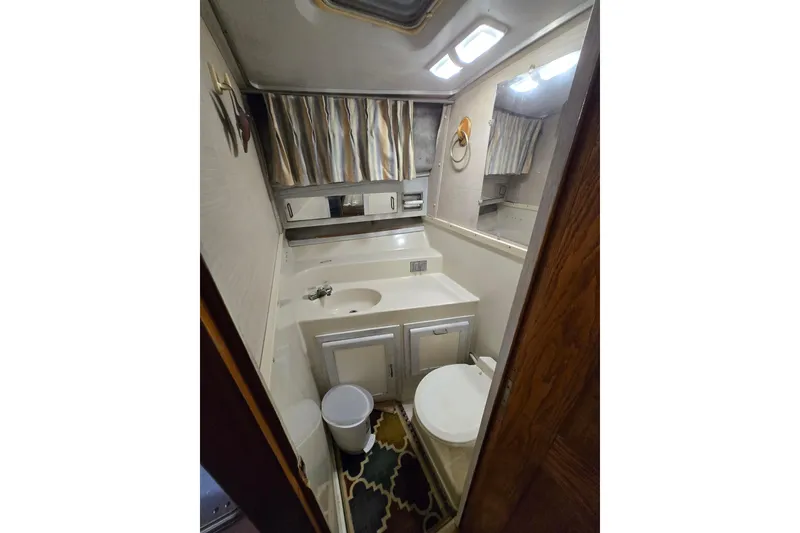 Slide: The Image of 1988 Mainship 36 Double Cabin bathroom with sink, toilet, mirror, and storage cabinets. - 26