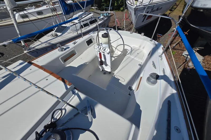 Slide: The Image of 1986 Pearson 303 Sloop sailboat cockpit with steering wheel and winches, docked among other boats. - 10