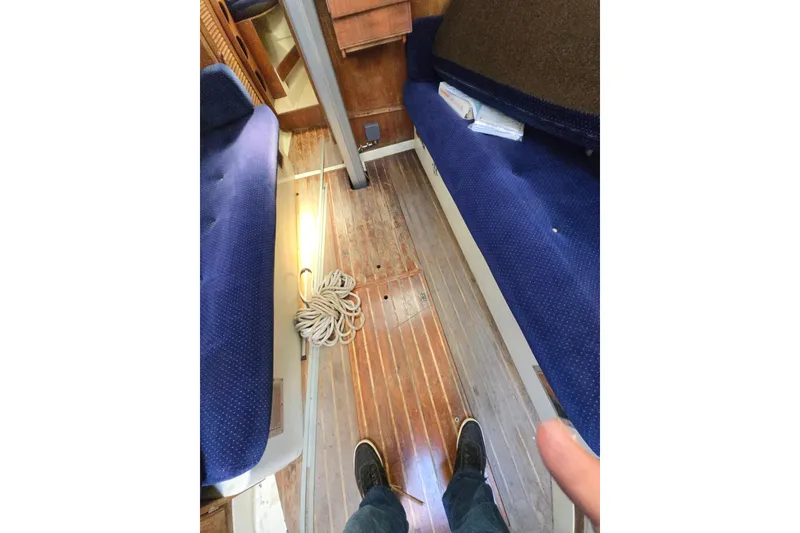 Slide: The Image of Interior of 1986 Pearson 303 Sloop with blue seating and wooden flooring. - 11