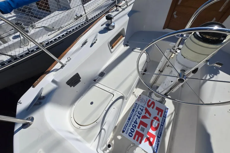 Slide: The Image of 1986 Pearson 303 Sloop cockpit with steering wheel, for sale sign visible. - 17