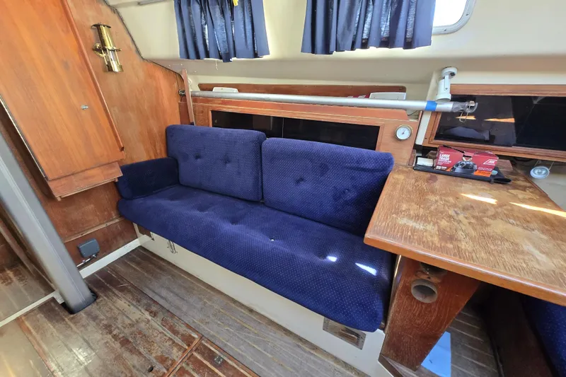 Slide: The Image of Interior of 1986 Pearson 303 Sloop with blue cushioned seating and wooden table. - 19