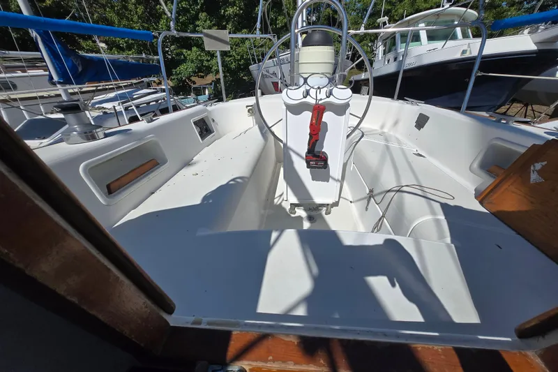 Slide: The Image of 1986 Pearson 303 Sloop cockpit with steering wheel and control panel, docked among other boats. - 24