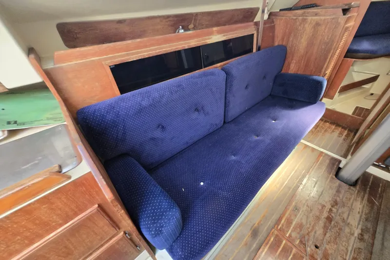 Slide: The Image of 1986 Pearson 303 Sloop interior with blue upholstered sofa and wooden accents. - 16